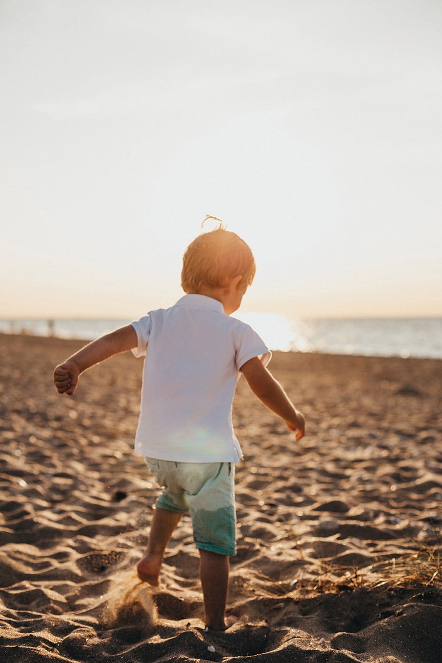 Niño jugando en la playa al atardecer